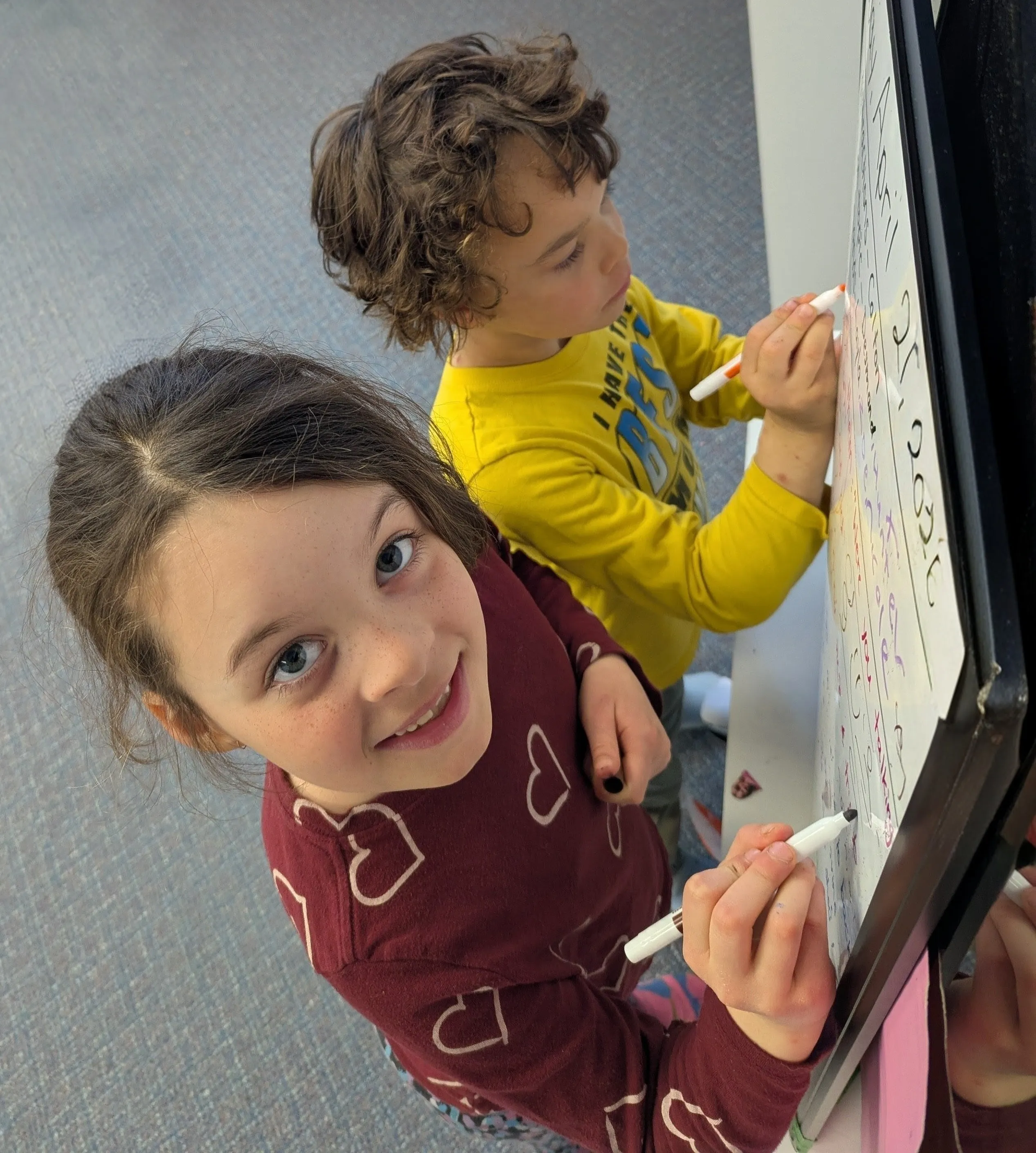 Two young learners writing on a whiteboard in the studio